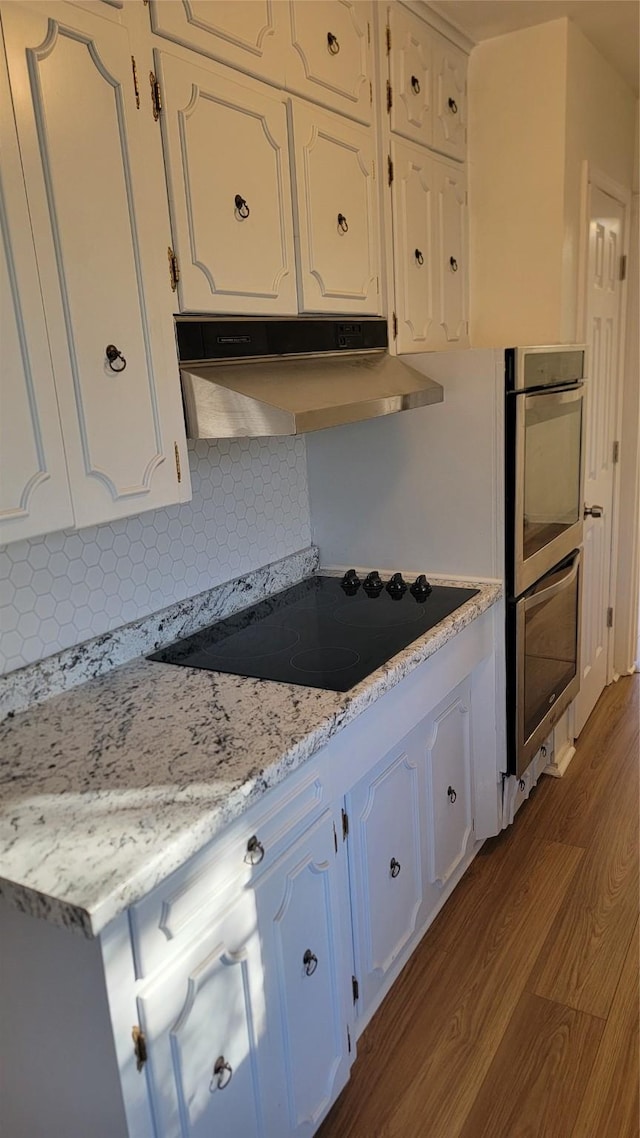2001 Alma, Sherman, TX 75090 - kitchen with black electric cooktop, under cabinet range hood, stainless steel double oven, dark wood finished floors, and white cabinetry