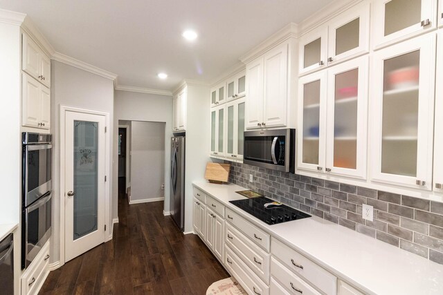 kitchen featuring a breakfast bar, white cabinets, ornamental molding, appliances with stainless steel finishes, and dark hardwood / wood-style flooring