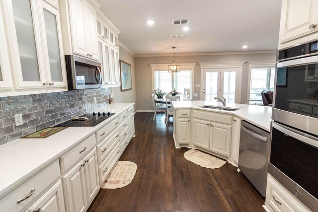 kitchen featuring white cabinetry, dark hardwood / wood-style floors, crown molding, decorative backsplash, and appliances with stainless steel finishes