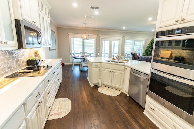 kitchen with dark hardwood / wood-style flooring, backsplash, stainless steel appliances, sink, and white cabinetry