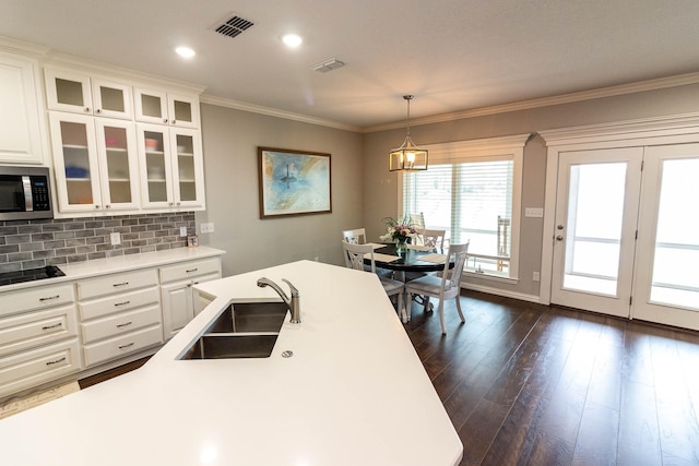 kitchen featuring glass insert cabinets, light countertops, stainless steel microwave, and a sink