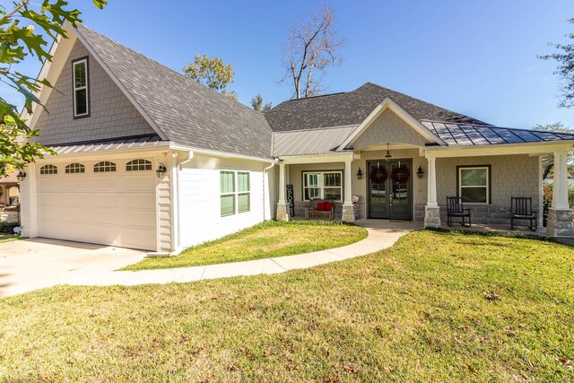 craftsman inspired home with a porch, a garage, french doors, and a front lawn