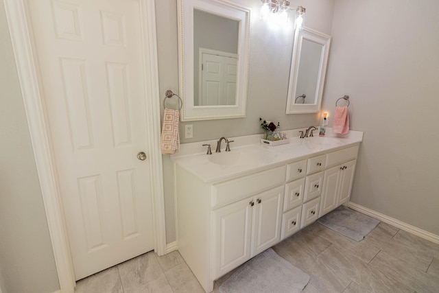 full bathroom featuring double vanity, a sink, and baseboards