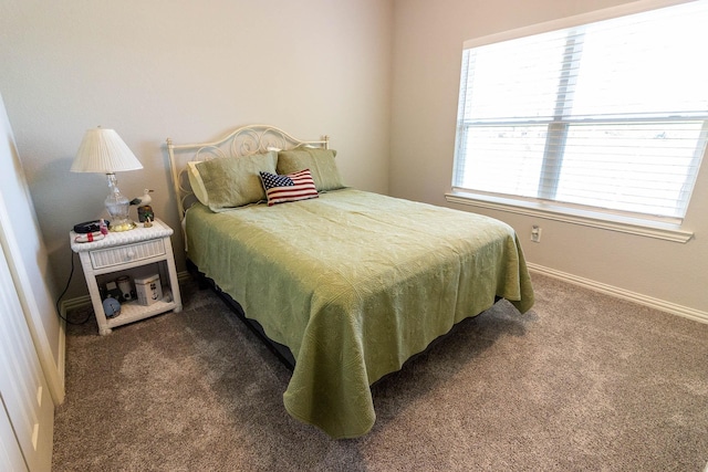 bedroom with dark colored carpet and baseboards