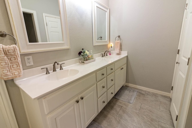 bathroom featuring double vanity, baseboards, a sink, and tile patterned floors