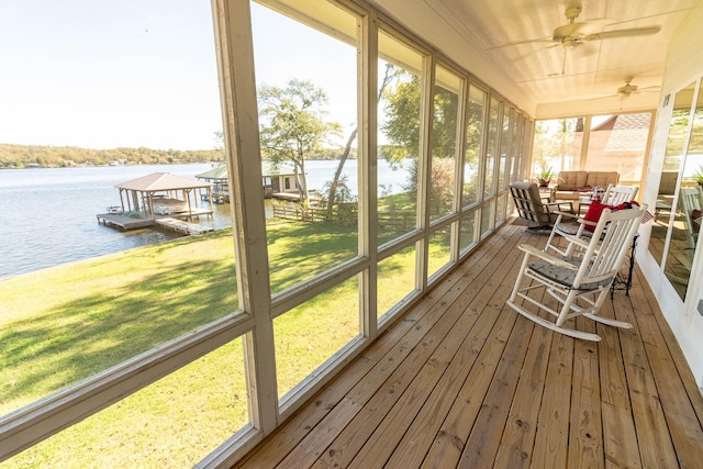 sunroom with a ceiling fan, a wealth of natural light, and a water view