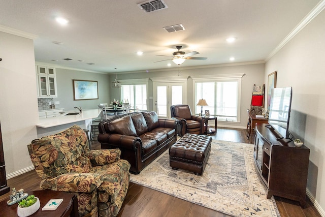 living area with baseboards, visible vents, ceiling fan, ornamental molding, and wood finished floors