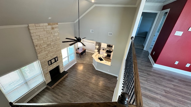 living room featuring a fireplace, dark hardwood / wood-style flooring, ceiling fan, and crown molding