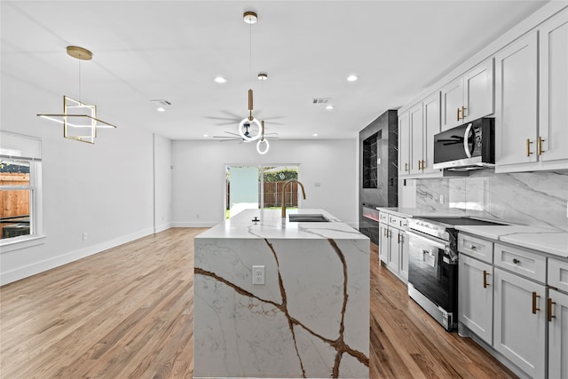 kitchen with decorative light fixtures, light wood-type flooring, stainless steel appliances, and light stone counters