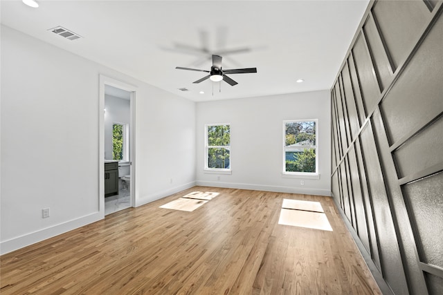 empty room featuring ceiling fan, a healthy amount of sunlight, and light hardwood / wood-style flooring