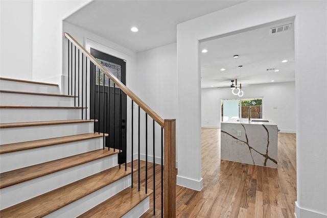 stairs featuring hardwood / wood-style flooring and ceiling fan