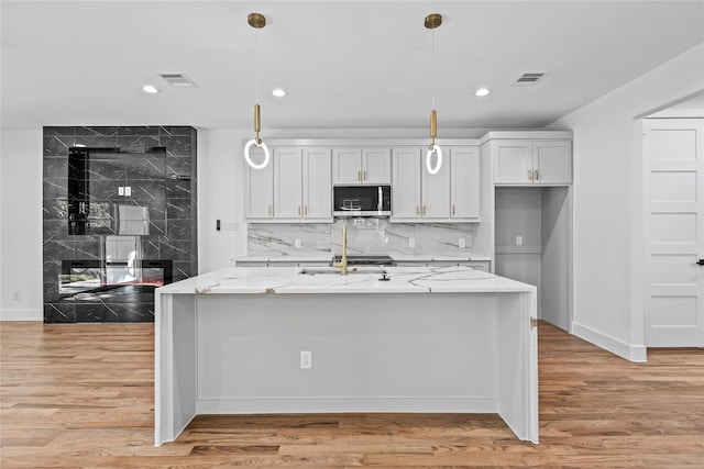 kitchen with white cabinets, decorative light fixtures, and light stone countertops