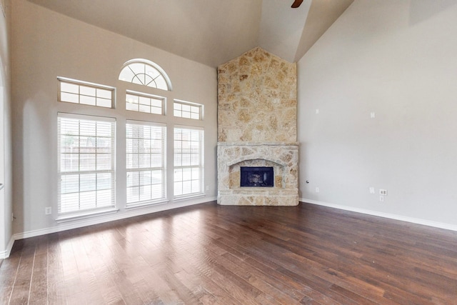 unfurnished living room with dark hardwood / wood-style floors, a stone fireplace, and high vaulted ceiling