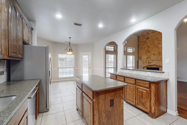 kitchen with pendant lighting, a center island, light tile patterned floors, and stainless steel dishwasher