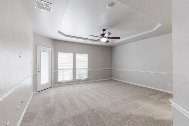 carpeted empty room featuring ceiling fan and a tray ceiling