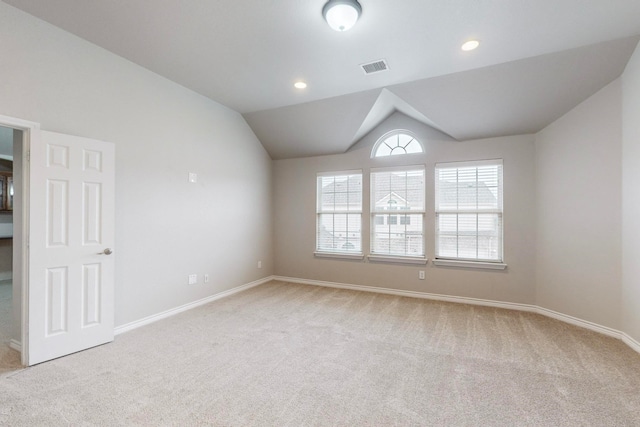 carpeted spare room featuring vaulted ceiling