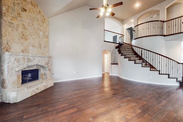 unfurnished living room with a fireplace, ceiling fan, dark hardwood / wood-style flooring, and high vaulted ceiling