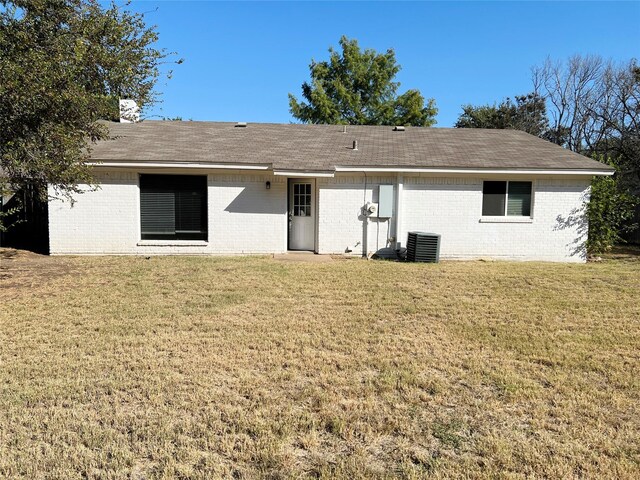 back of property featuring a lawn and cooling unit