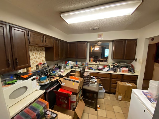 kitchen featuring dark brown cabinets, light tile patterned flooring, and a textured ceiling