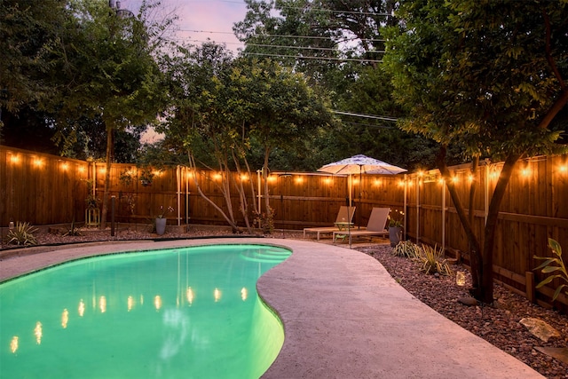 pool at dusk with a patio area