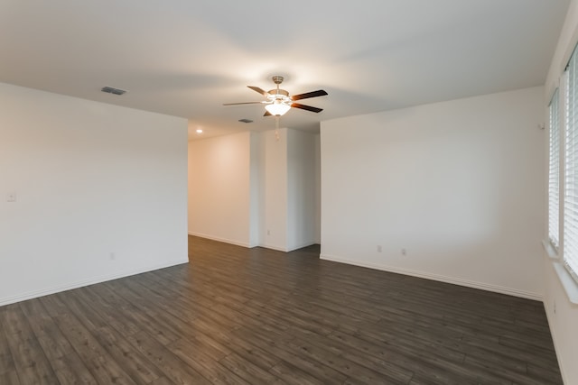 spare room featuring a wealth of natural light, ceiling fan, and dark wood-type flooring