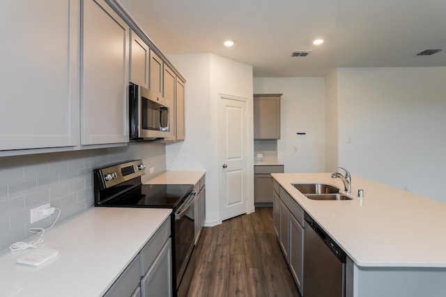 kitchen featuring backsplash, sink, dark hardwood / wood-style floors, gray cabinets, and appliances with stainless steel finishes