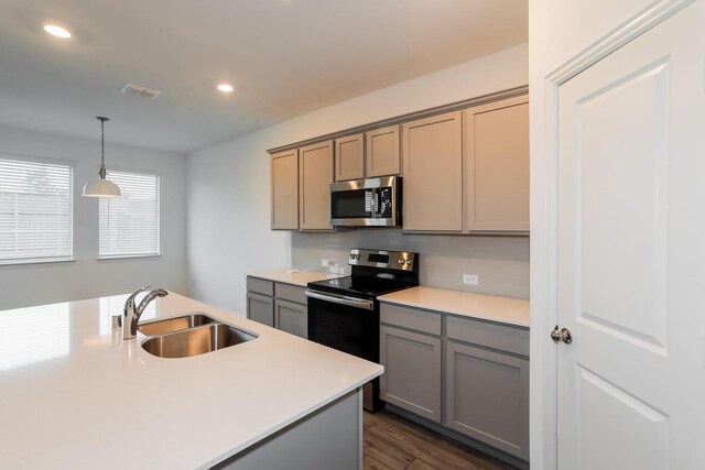 kitchen with appliances with stainless steel finishes, dark wood-type flooring, sink, pendant lighting, and gray cabinets