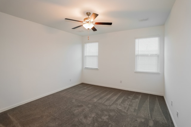 spare room featuring dark colored carpet, plenty of natural light, and ceiling fan