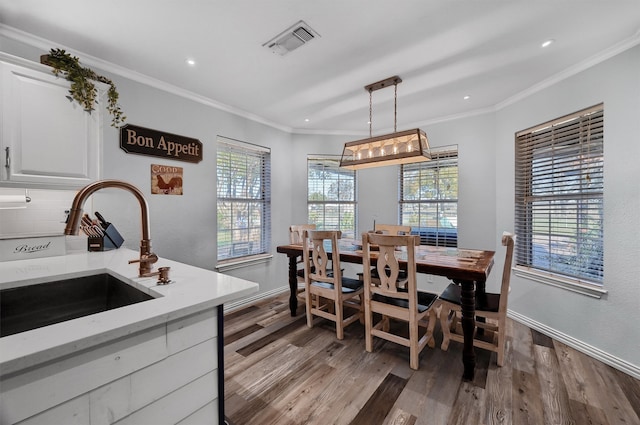 dining area featuring crown molding, sink, and light wood-type flooring