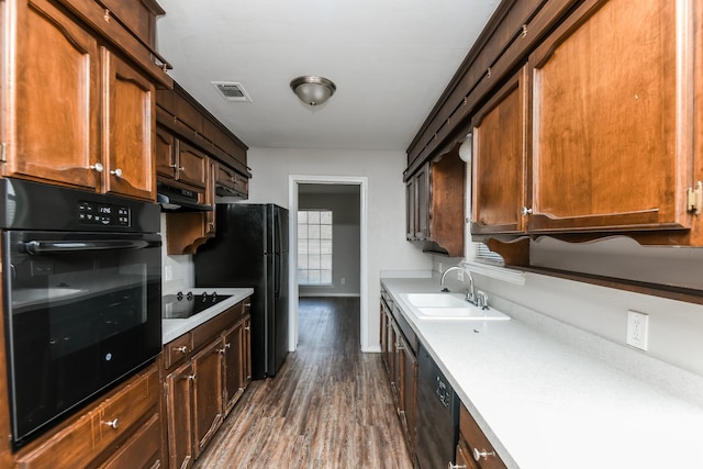 kitchen featuring black appliances, dark hardwood / wood-style flooring, and sink