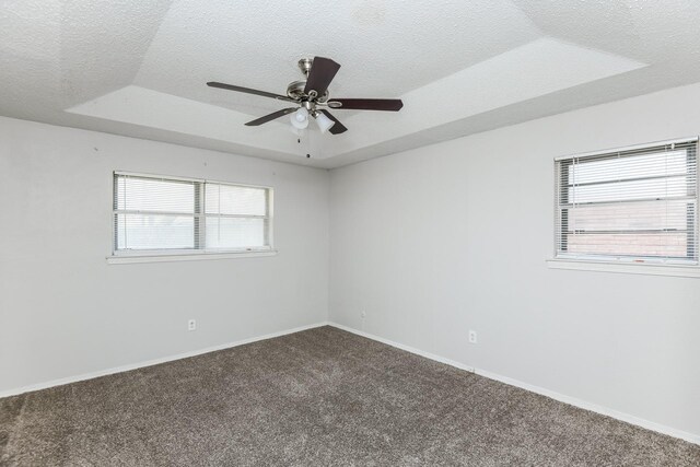 carpeted spare room with a textured ceiling, a raised ceiling, plenty of natural light, and ceiling fan