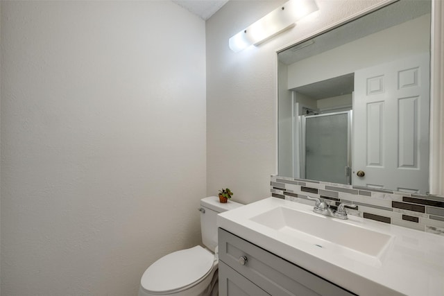 bathroom featuring vanity, backsplash, toilet, and walk in shower