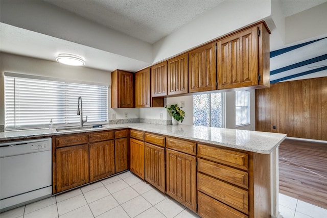 kitchen with sink, a textured ceiling, plenty of natural light, dishwasher, and kitchen peninsula