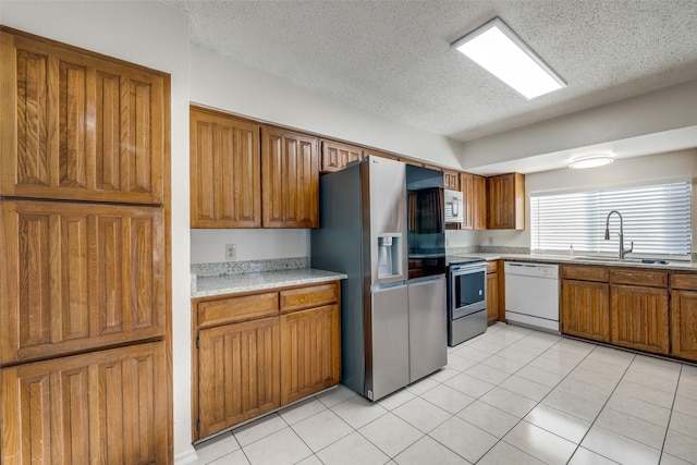 kitchen with sink, light tile patterned flooring, a textured ceiling, and appliances with stainless steel finishes