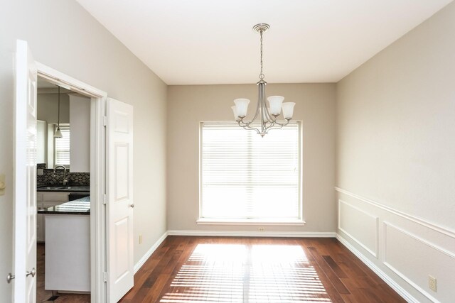 unfurnished dining area with dark hardwood / wood-style flooring, plenty of natural light, and a notable chandelier