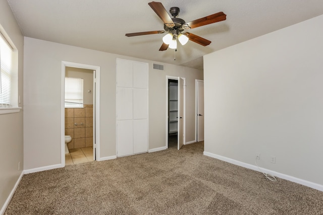 unfurnished bedroom with ceiling fan, light carpet, and connected bathroom