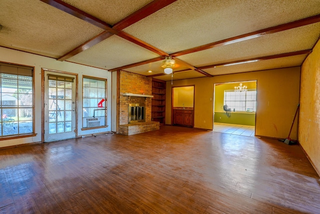 unfurnished living room featuring a fireplace, beam ceiling, a textured ceiling, and hardwood / wood-style flooring