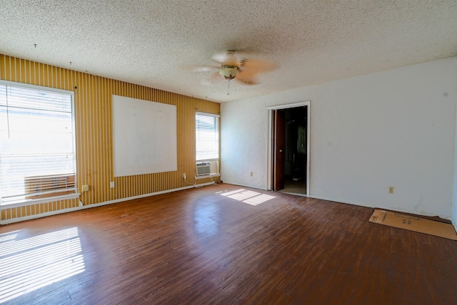 spare room featuring ceiling fan, wood walls, a textured ceiling, and hardwood / wood-style flooring