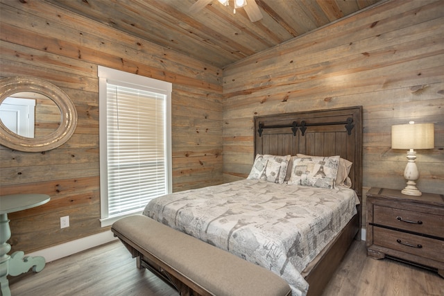 bedroom with ceiling fan, wood-type flooring, wood ceiling, and wood walls