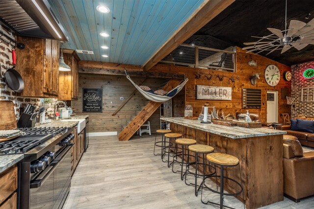 bar with ceiling fan, brick wall, wooden walls, and light wood-type flooring