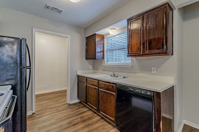 kitchen with light wood-type flooring, dark brown cabinetry, sink, and black appliances