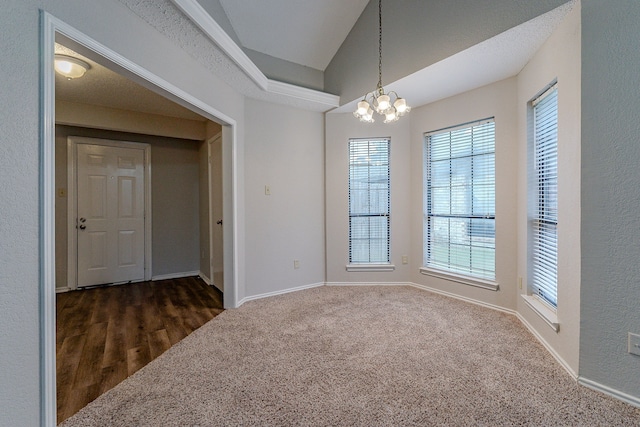 carpeted spare room with an inviting chandelier and lofted ceiling