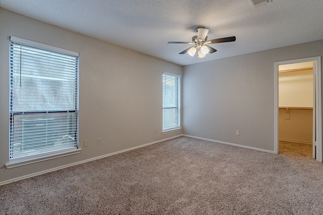 unfurnished room with carpet, ceiling fan, and a textured ceiling