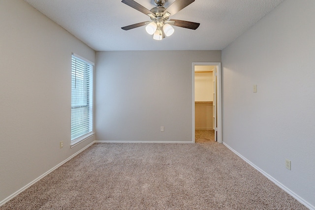 carpeted empty room with ceiling fan and a textured ceiling