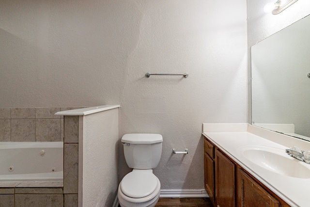 bathroom with vanity, a relaxing tiled tub, and toilet