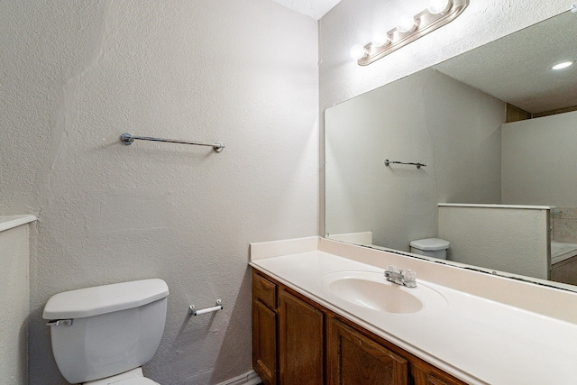 bathroom with vanity, a textured ceiling, and toilet