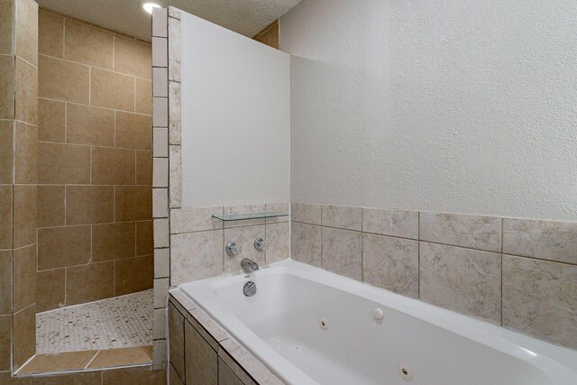 bathroom featuring a textured ceiling and tiled bath