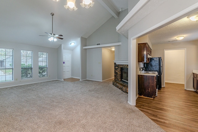 living room with ceiling fan, beam ceiling, a fireplace, a textured ceiling, and light carpet