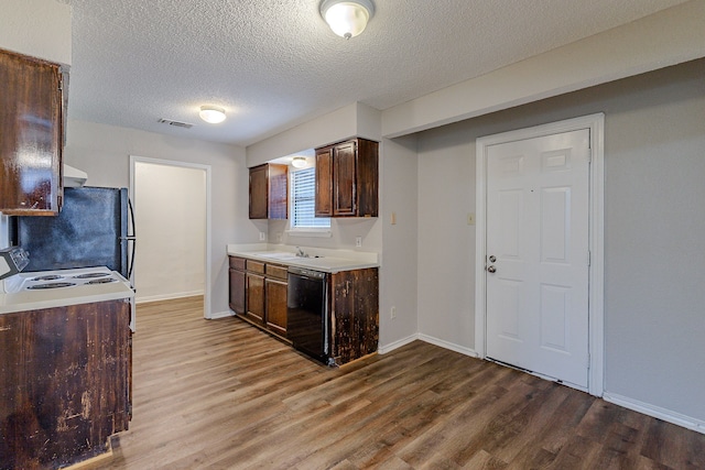 kitchen featuring sink, black dishwasher, hardwood / wood-style floors, refrigerator, and a textured ceiling