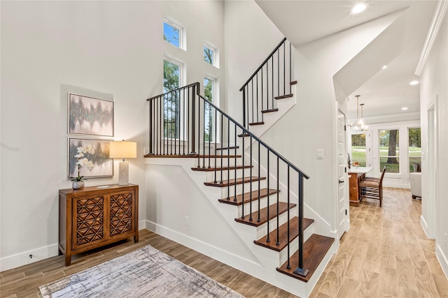 stairway with a high ceiling, hardwood / wood-style floors, and an inviting chandelier